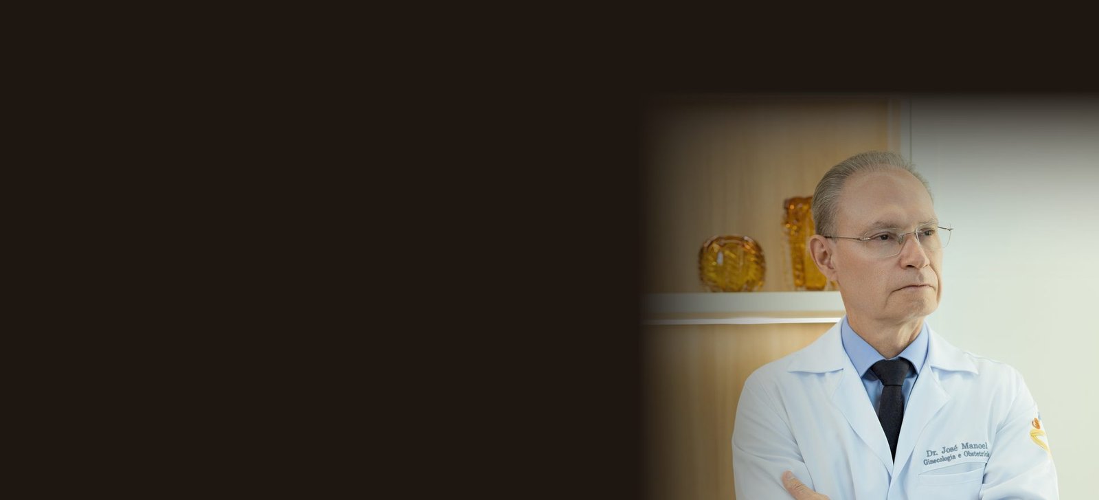 Dr. José Manoel de jaleco branco no consultório