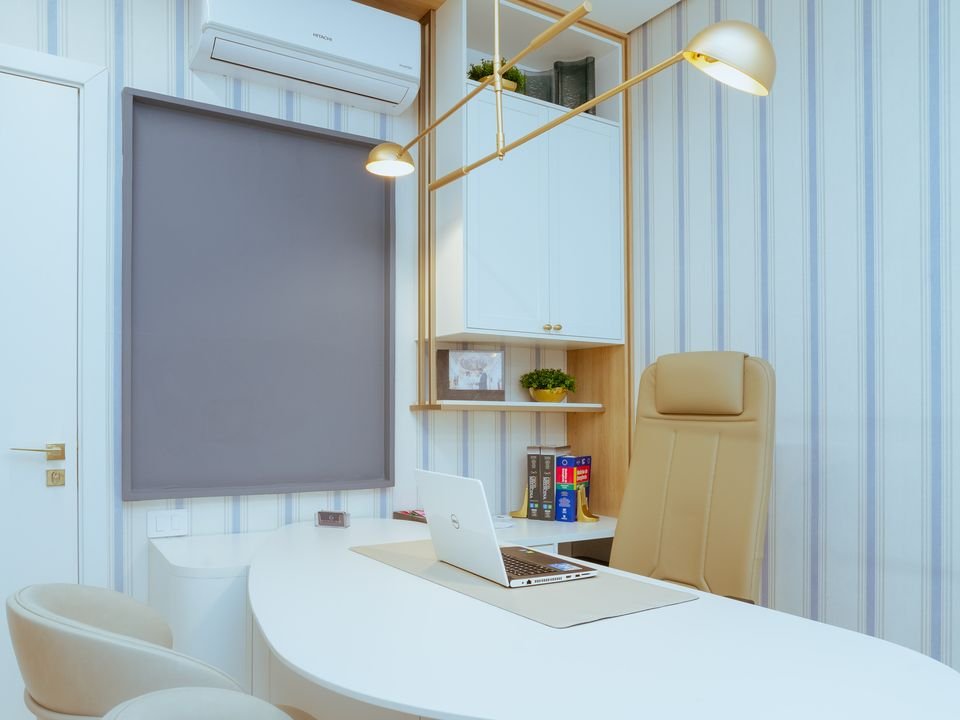 Sala de atendimento com mesa oval clara e cadeiras estofadas