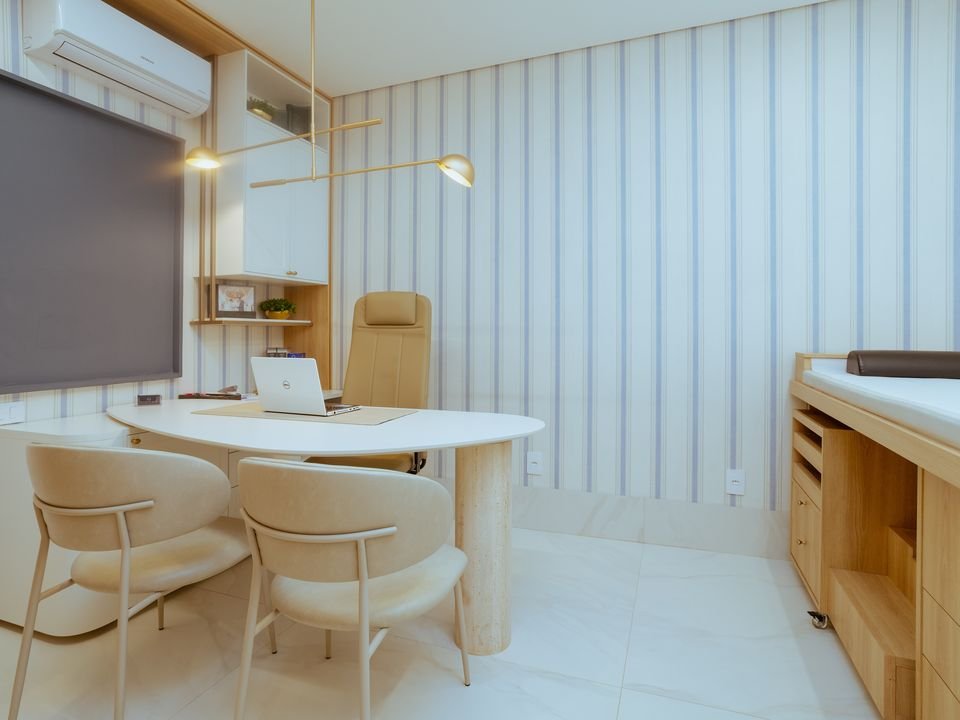 Consultório de atendimento, com mesa clara e cadeiras estofadas