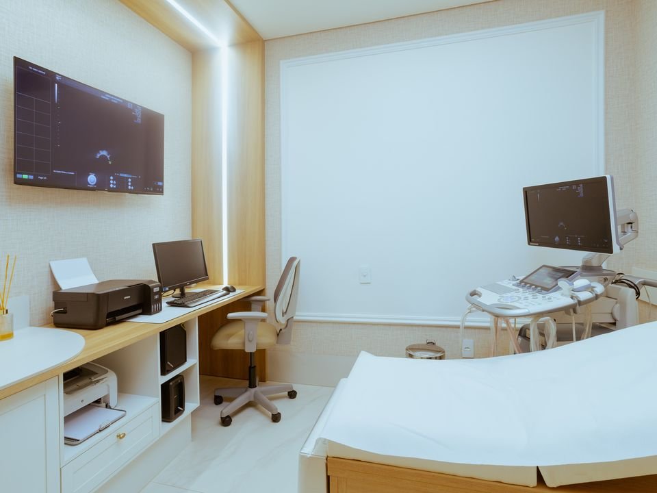 Sala de exames com maca e equipamento de imagem