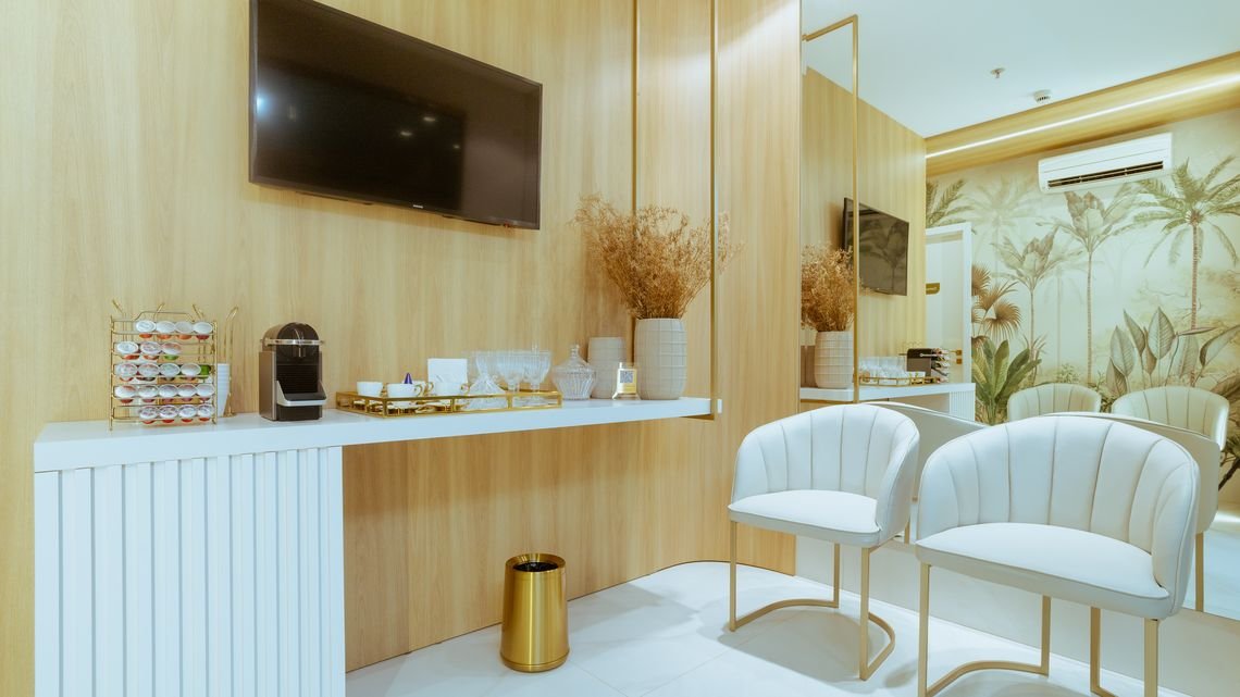 Sala de espera do consultório, com poltronas claras e bancada de apoio