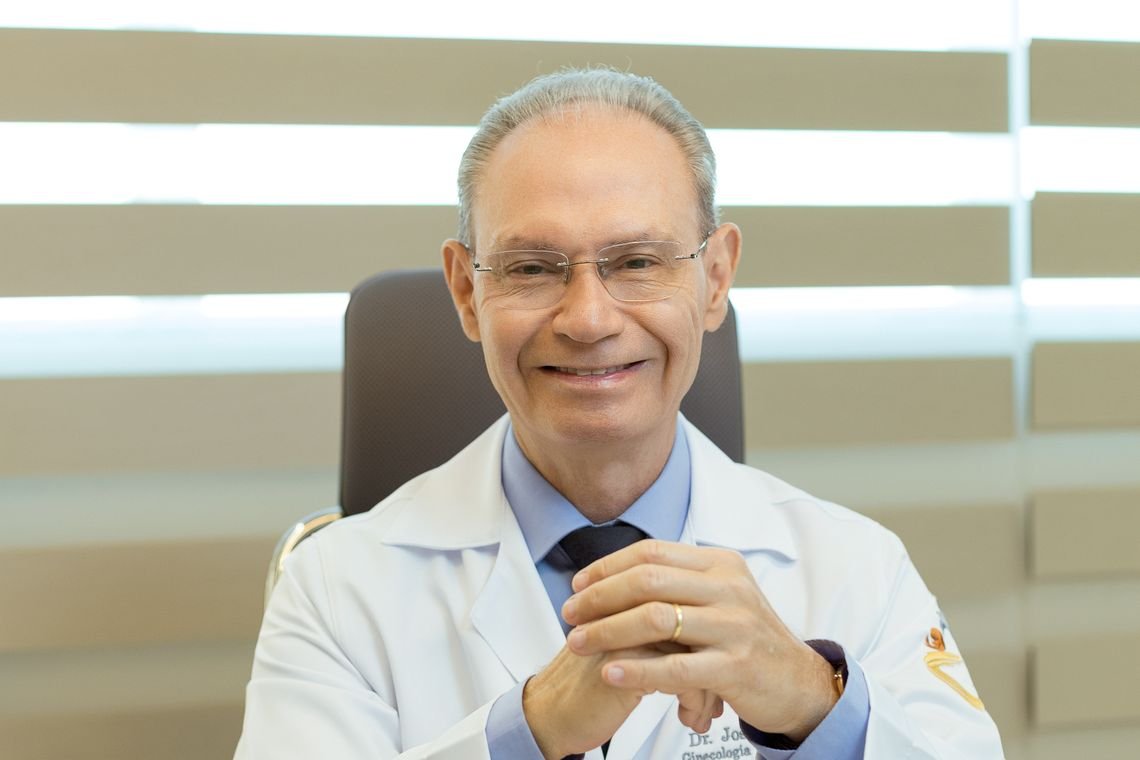 Dr. José Manoel sorrindo à mesa do consultório