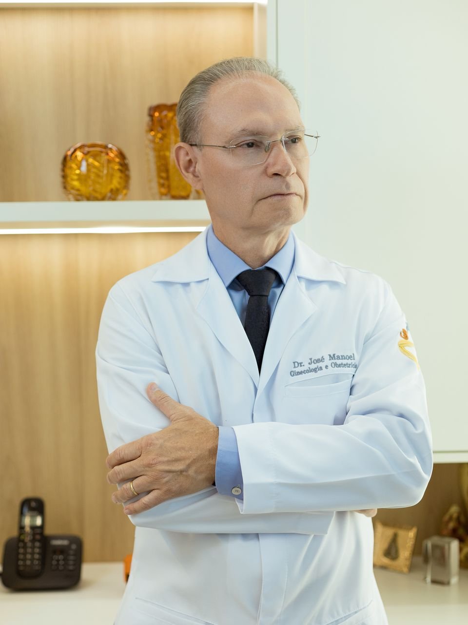 Dr. José Manoel de jaleco branco no consultório